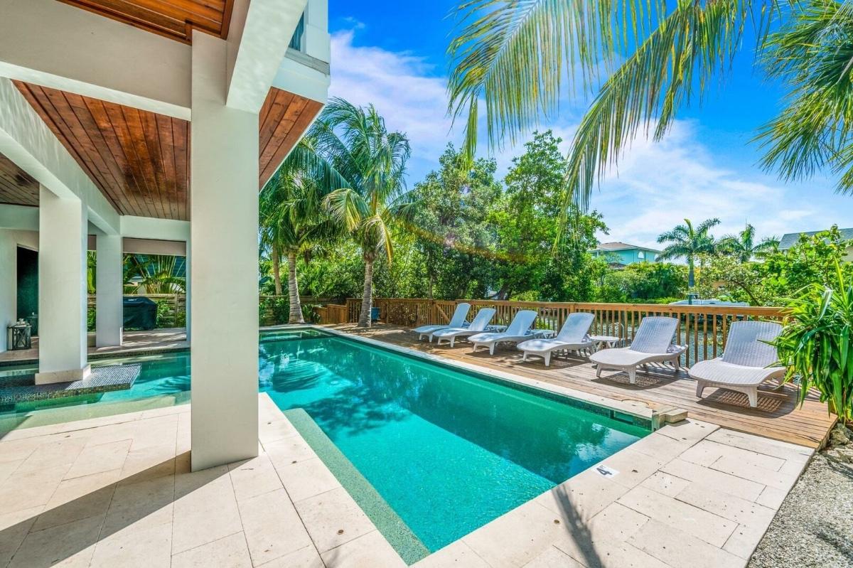 Golden hour on Anna Maria Island. In the foreground are beautiful homes, while the ocean and sunset can be seen in the distance. The homes all have a lush, tropical feel - perfect for your next Anna Maria Island luxury vacation!