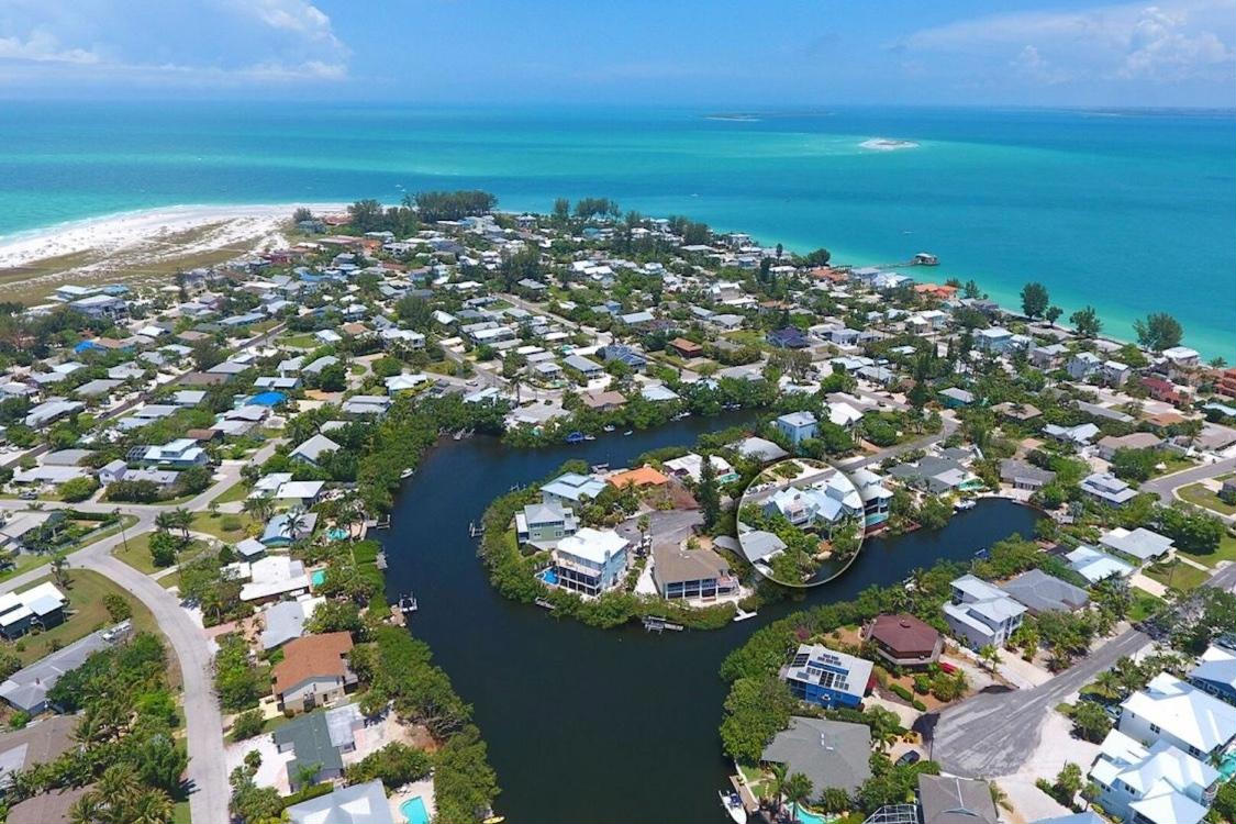 Aerial view of our AcquaLuxe property, and the surrounding area, at sunset. This waterfront luxury vacation rental on Anna Maria Island is one of many offered by Once Upon a Beach, and boasts a heated saltwater pool, private dock, chef’s kitchen, and top-tier amenities for an unforgettable coastal retreat.