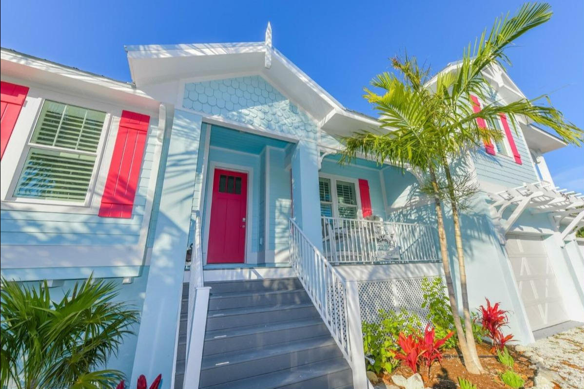 Our 'She's Always Right' Anna Maria Island luxury vacation rental, a soft blue house with white trim and coral-colored doors. This property, along with many others, is pet friendly! There's no need to leave your furry friend at home. They deserve a pet vacation!